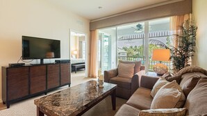 A hotel room with a flat-screen TV on a wooden cabinet, a marble coffee table, a beige sofa, and a view of the outside balcony. - GreenLinks/Updated Lely Condo; w/Office space-Lake Views-Resort Amenities (Naples)