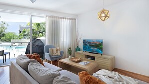 Un salon moderne avec un canapé, un téléviseur et une vue sur la piscine.