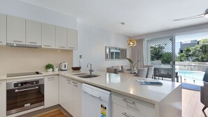 Une cuisine moderne avec des meubles blancs, un lave-vaisselle et un coin repas comprenant une table et des chaises.