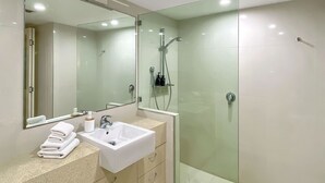 Un bagno moderno con doccia vetrata, lavabo bianco e un ampio specchio.