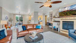 A spacious living room with a brown leather sofa, a round coffee table, and a fireplace. - Experience luxury in this 3-bedroom home with stunning red rock views in Sedona. (Sedona)