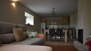 Un salon moderne avec un canapé, un coin repas avec des chaises et une cuisine en arrière-plan.