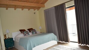 Une chambre à coucher avec un lit, des tables de chevet, une fenêtre avec des rideaux et un plafond en bois.