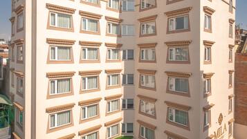 A multi-story hotel with a green rooftop terrace, multiple windows, and a visible entrance.