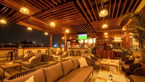 A rooftop bar with wooden ceiling beams, comfortable seating, and a flat-screen TV. - Mila Hotel (Kathmandu)