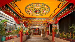 A corridor with ornate ceiling decorations and potted plants. - Mila Hotel (Kathmandu)