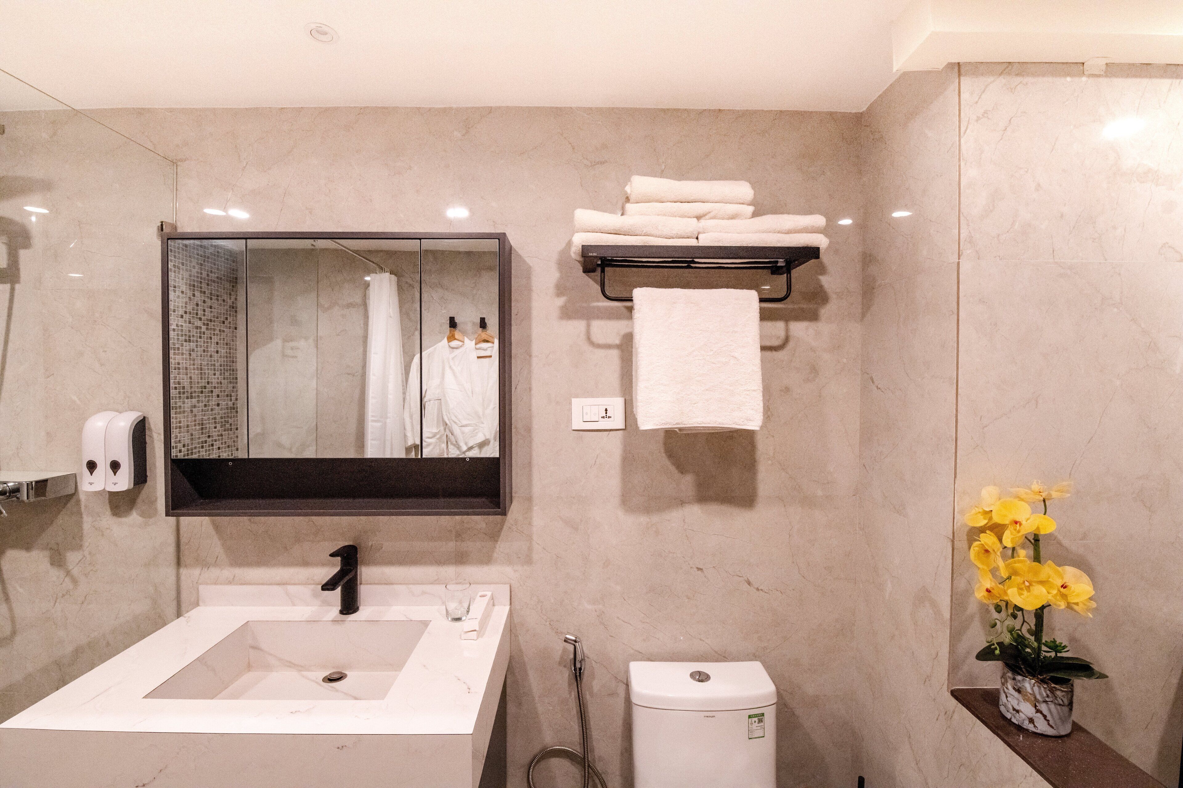 A modern bathroom with a large mirror, a sink, a toilet, and a towel rack.