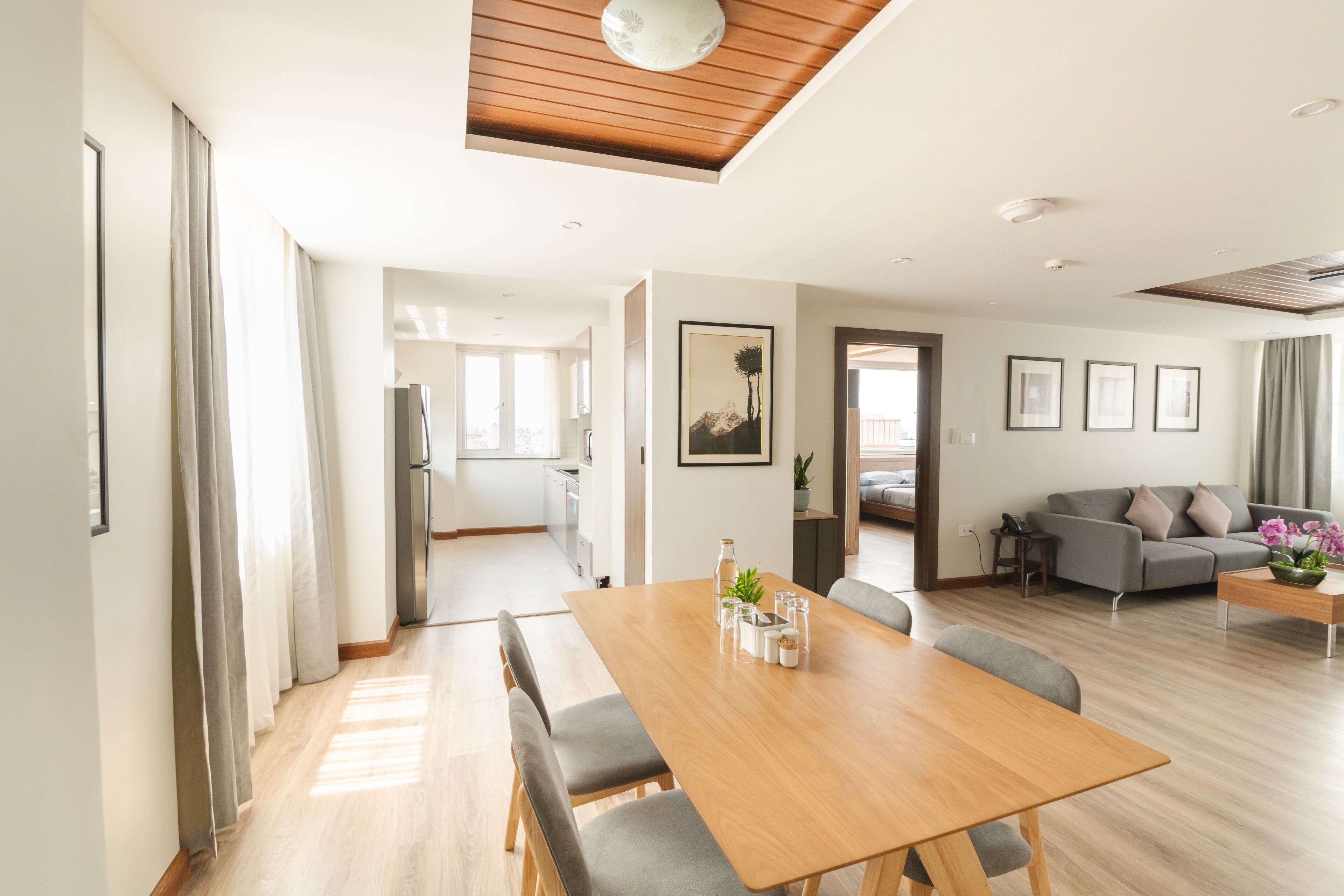 Un espacio habitable amplio con una mesa de comedor de madera, sofás grises y una cocina al fondo.