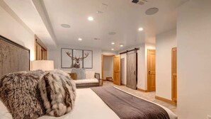 Una habitación de hotel moderna con una cama grande, un plaid suave, una obra de arte con un ciervo enmarcado y un armario con puerta corredera.