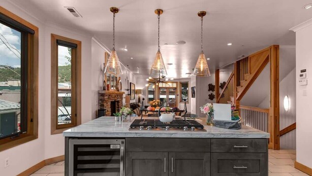 Una cocina con una isla grande, luces colgantes y vistas al exterior.