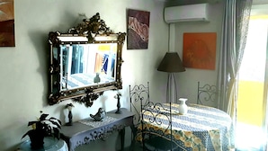Ein Zimmer mit Spiegel, Tisch mit gemustertem Tischläufer, Lampe und dekorativen Gegenständen auf einer Konsole.