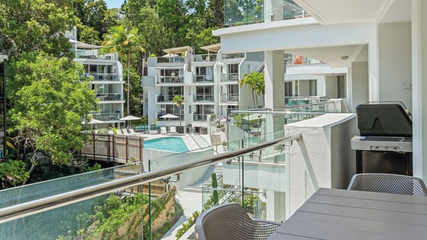 A balcony with a pool, lounge chairs, and a grill area. - Penthouse 9 - The Cove (Noosa Heads)