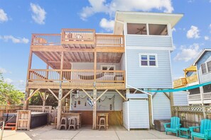 A multi-level wooden structure with a balcony, a small enclosed area with a table and chairs, and a separate building with a window. - Private Pool, Hot Tub! Entertainment Area! Tiki Bar (Corolla)