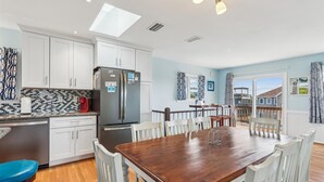 Una cucina moderna con mobili bianchi, un frigorifero nero e un tavolo da pranzo in legno con sedie bianche.