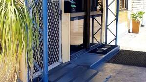 A building entrance with a metal gate, a payphone, and a sign indicating 'STAFF ONLY'.