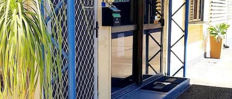A building entrance with a metal gate, a payphone, and a sign indicating 'STAFF ONLY'.
