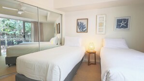 A hotel room with two beds, a large mirror, and artwork on the wall.
