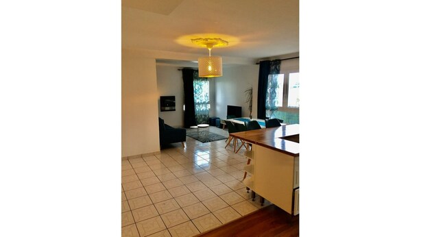 A spacious living area with a dining table, a sofa, and a TV. - Appartement Accueillant à une Demi-heure de Paris (Viry-Châtillon)