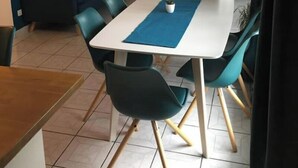 A dining area with a white table, teal chairs, and a blue placemat. - Appartement Accueillant à une Demi-heure de Paris (Viry-Châtillon)