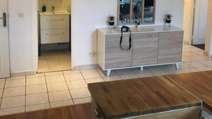A modern living room with a wooden coffee table, a white cabinet with a mirror, and a tiled floor. - Appartement Accueillant à une Demi-heure de Paris (Viry-Châtillon)