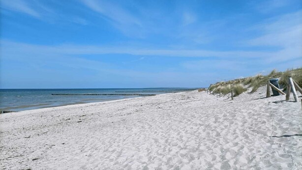A sandy beach with a clear blue sky and calm sea. - Bungalow am Strand für die Ganze Familie (Insel Poel)