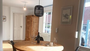 A dining area with a round wooden table, black chairs, and a hanging light fixture. - Bungalow am Strand für die Ganze Familie (Insel Poel)