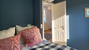 A bedroom with a bed, pillows, a white door, and a view of the hallway. - Bungalow am Strand für die Ganze Familie (Insel Poel)