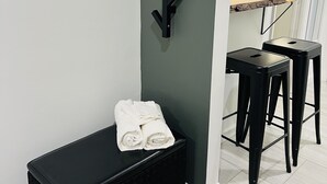 Un coin de pièce avec un banc noir, un élément de décoration noire fixé au mur et deux tabourets de bar noirs.