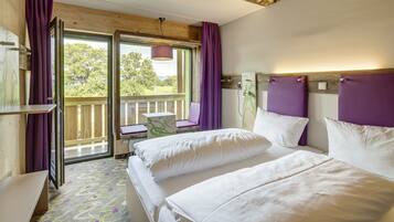 Une chambre d’hôtel avec deux lits, un bureau et une fenêtre avec des rideaux violets.