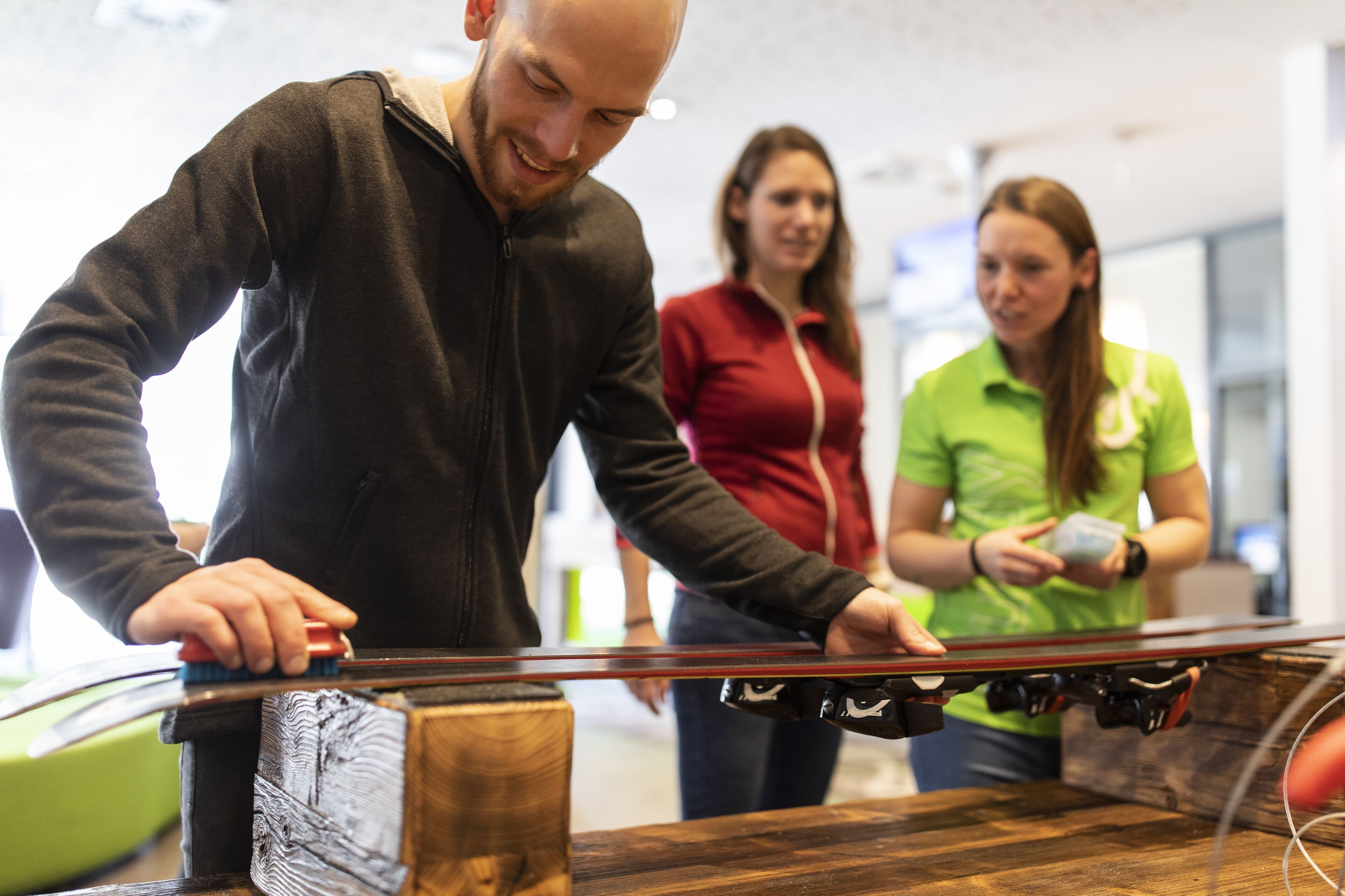 En person justerer et skateboard på et træbord i et rum med moderne indretning.