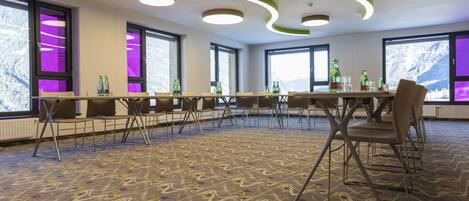 A conference room with a long table, chairs, and large windows with a mountain view.