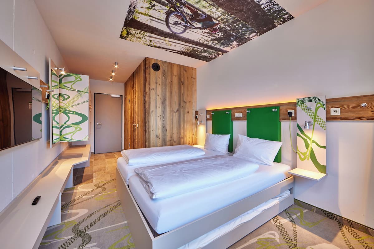 Ein modernes Hotelzimmer mit einem großen Bett, einem Fernseher und einer Wand in Grünton.