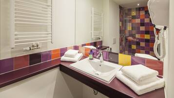 Une salle de bain moderne avec un lavabo blanc, un miroir, un porte-serviettes et un espace douche.
