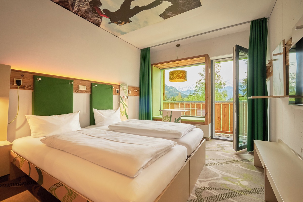 A hotel room with a bed, a desk, a chair, and a view of the outdoors.