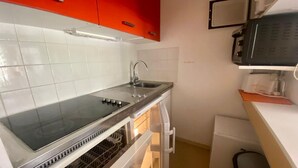 Une cuisine compacte dotée d’un plan de travail en acier inoxydable, d’un évier et d’un lave-vaisselle.