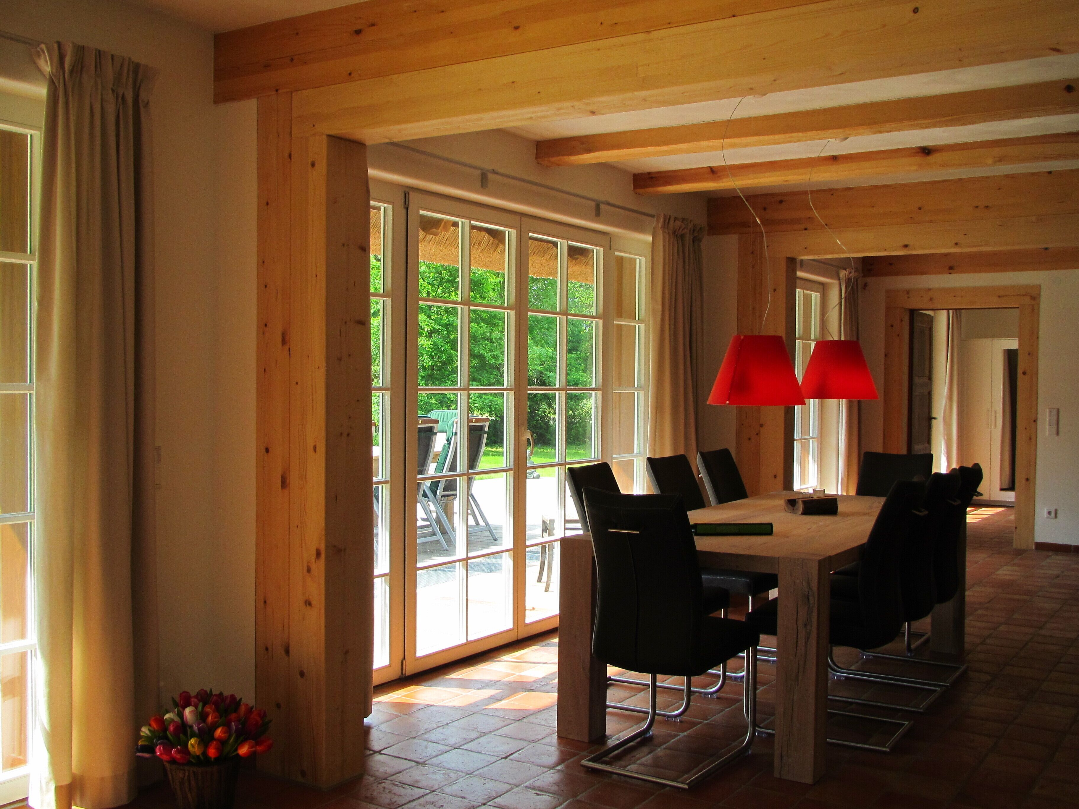 Un espace repas avec une table en bois, des chaises noires et une suspension rouge.