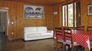 Una habitación con paneles de madera, un sofá blanco, una mesa de comedor con mantel rojo y una lámpara de araña.