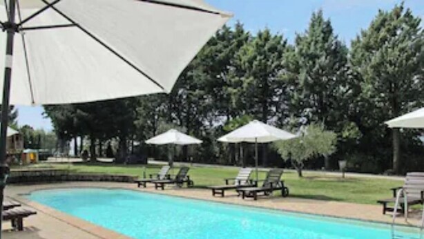 Piscina con sillones de descanso y sombrillas.