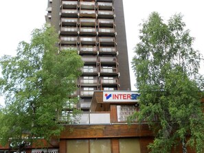 A high-rise building with multiple balconies and a sign for 'INTERSPACES'. - 3-room apartment at the foot of the slopes with balcony (Le Corbier)