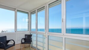 A room with large windows, a wooden floor, and two black chairs. - Modern Apartment in Salou with Sea View (Salou)