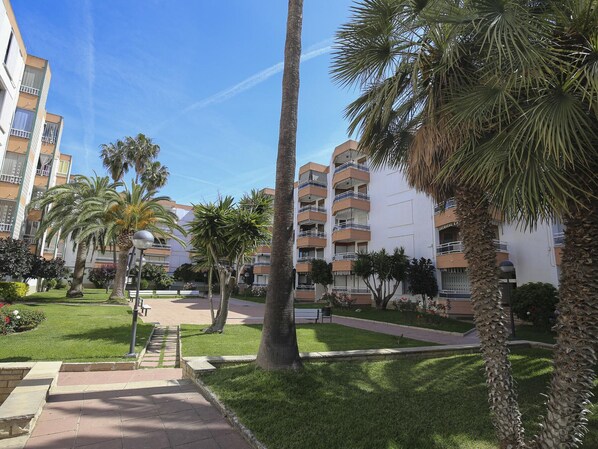 Un barrio residencial con edificios de apartamentos, palmeras y un césped bien cuidado.