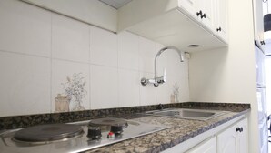 Eine Küche mit weißen Schränken, einer Granit-Arbeitsplatte, einem Edelstahl-Spülbecken und einem Gasherd.
