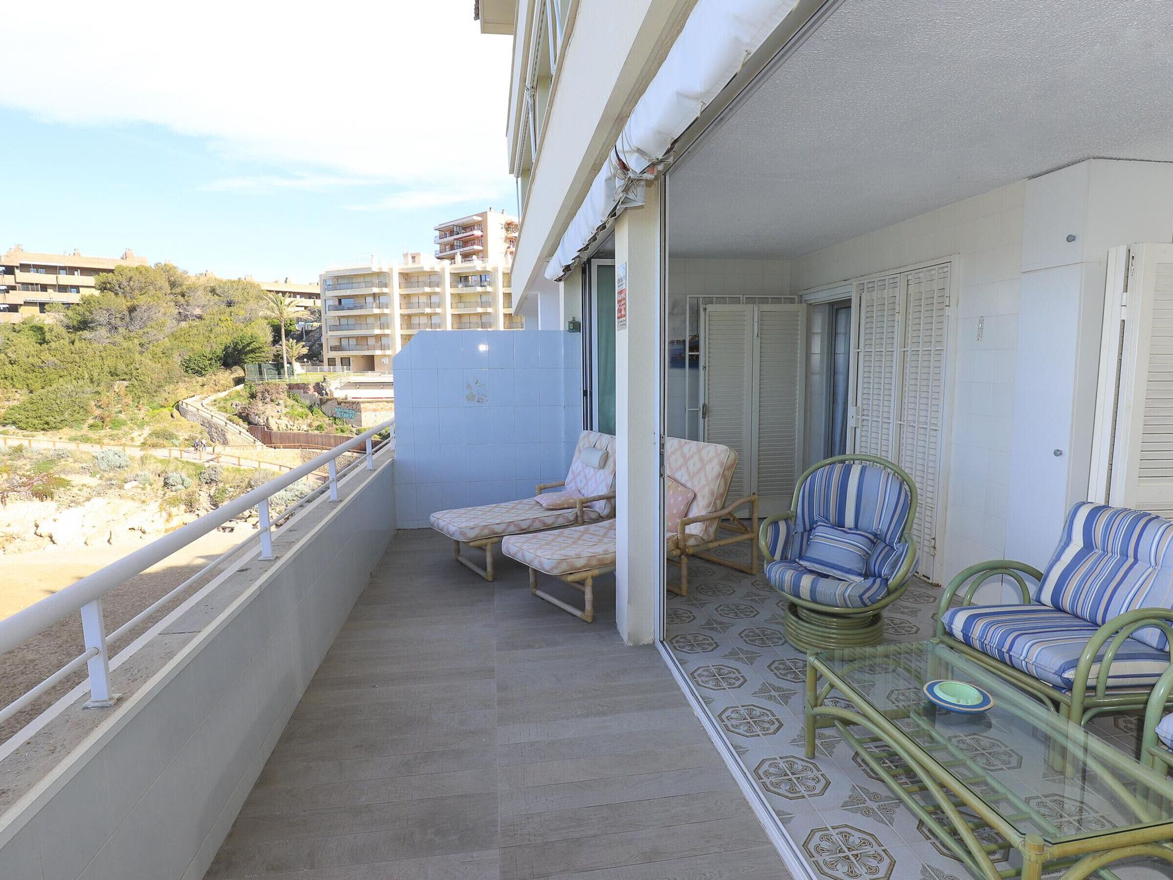 Een balkon met twee lounge fauteuils, een klein tafeltje en een glazen bijzettafeltje.