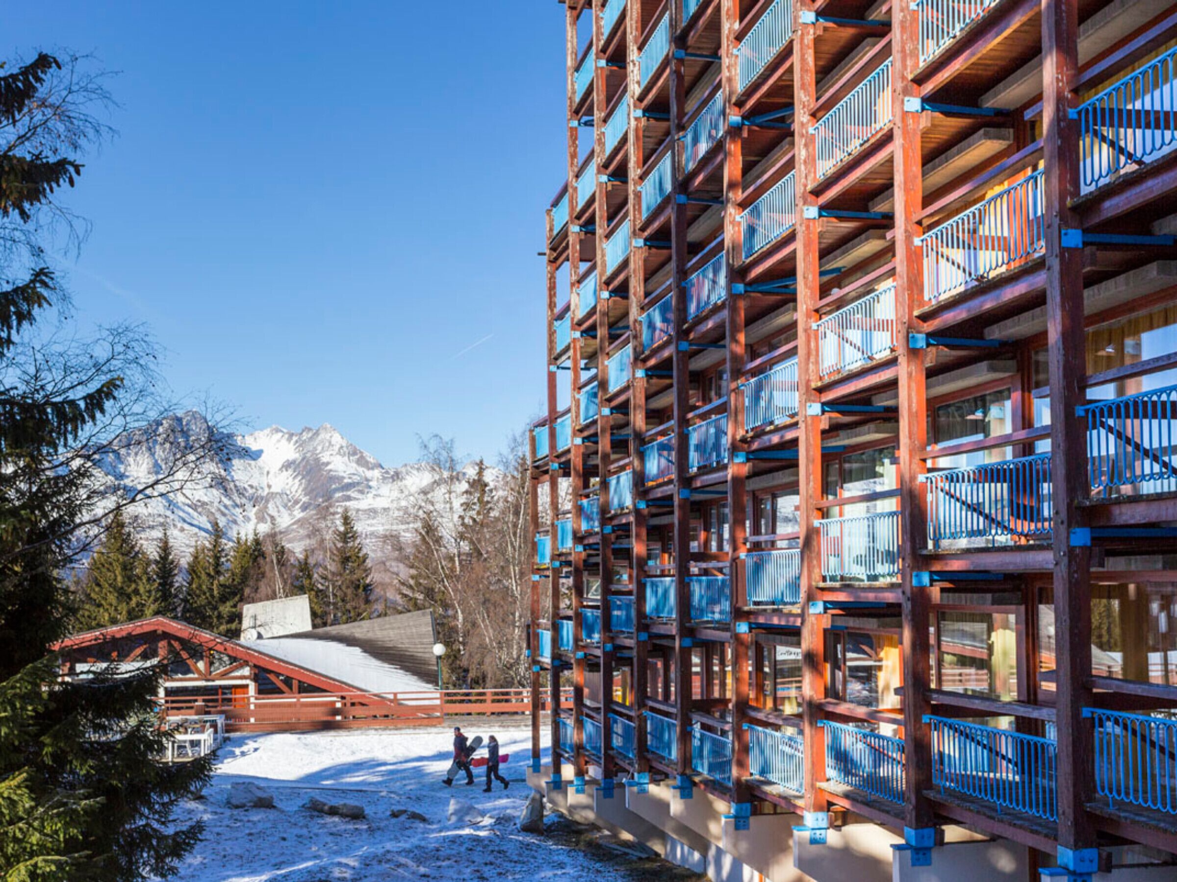 A multi-story building with balconies, a ski lift, and snow-covered ground.