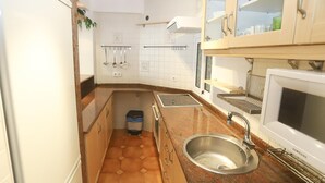 Una cocina pequeña con un lavabo, estufa y armarios.