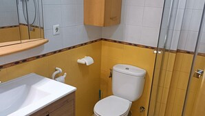 Un baño con un lavamanos blanco, inodoro y cabina de ducha.