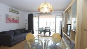 Una sala moderna con una mesa de comedor de vidrio, un sofá gris y una lámpara colgante.