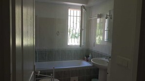 A bathroom with a bathtub, a sink, and a window. - Rez-de-villa (LE BEAUSSET)