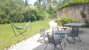 A patio with a table and chairs, a hammock, and a gravel path. - Rez-de-villa (LE BEAUSSET)