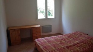 A bedroom with a wooden desk, a radiator, and a plaid bedspread. - Rez-de-villa (LE BEAUSSET)